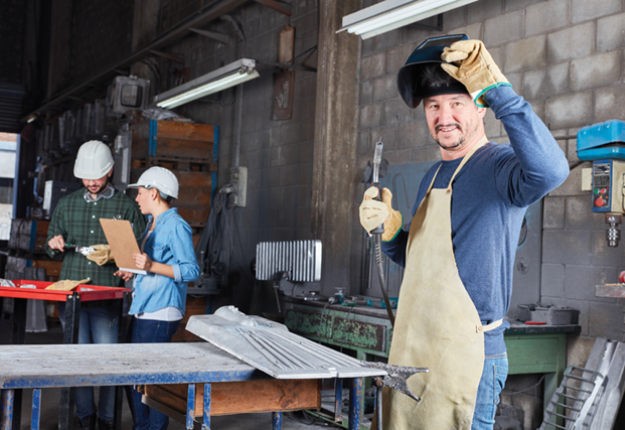 2 A man in a factory wearing an apron and hard hat, ready to work and ensure safety in the industrial setting.
