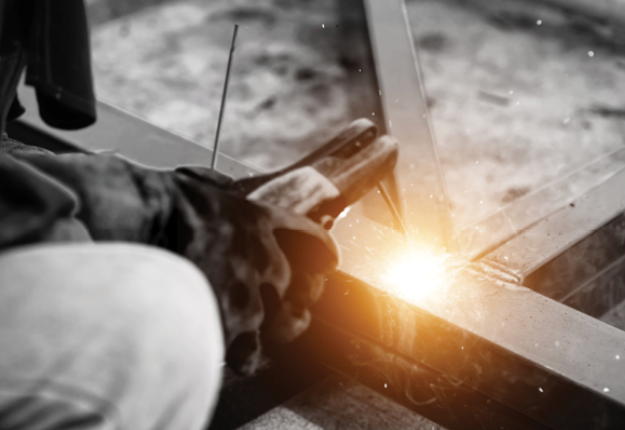 A person welding a metal beam.