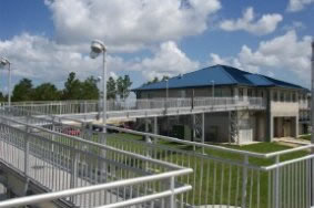 A ramped concrete walkway with aluminum handrails leading to a building